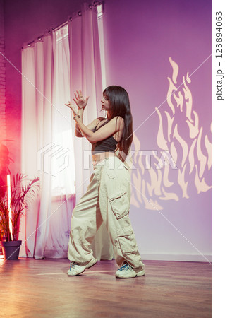 Dancer performs contemporary routine in studio with warm lighting and dynamic shadow patterns in the background Dancer performs contemporary routine in studio with warm lighting and dynamic shadow patterns in the background 123894063