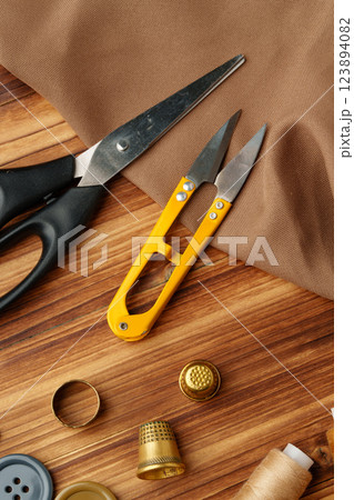 Crafting tools and materials arranged on a wooden table for sewing projects Crafting tools and materials arranged on a wooden table for sewing projects 123894082