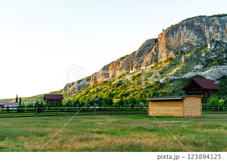 Sunset over a tranquil rural landscape with mountains and wooden structures in the foreground 123894125