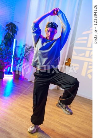 A young dancer poses in a dance studio with colorful lighting A young dancer poses in a dance studio with colorful lighting 123894126