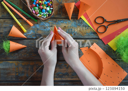 Carrots gift Bag for candies. DIY paper craft with your own hands together with children. Easter treat box. Art project for kids. Step by step guide. 123894150