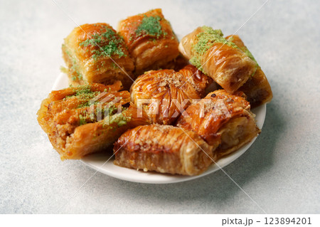 Delicious assortment of baklava pastries served on a white plate with nuts and syrup 123894201