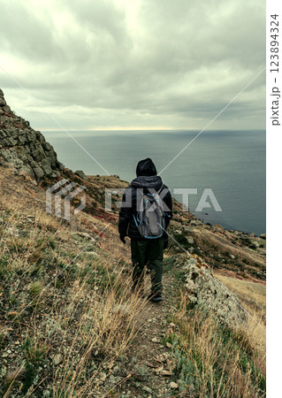 Hiker explores rugged coastline under moody skies near the ocean 123894324