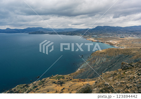 Scenic view of a tranquil lake surrounded by mountains and hills under a cloudy sky in southern region Scenic view of a tranquil lake surrounded by mountains and hills under a cloudy sky in southern region 123894442