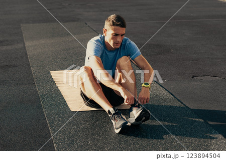 Fitness enthusiast stretching on an exercise mat during outdoor workout session at a park in the morning 123894504