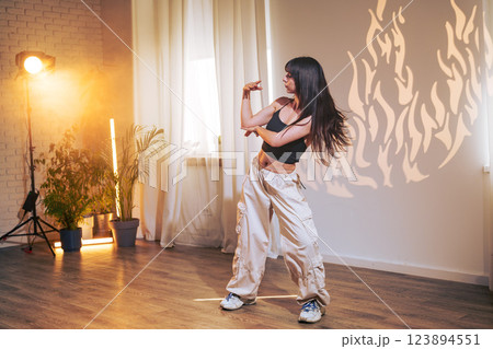 Dancer showcasing contemporary movements in a bright indoor studio with stylish decor and dramatic lighting Dancer showcasing contemporary movements in a bright indoor studio with stylish decor and dramatic lighting 123894551