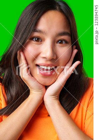 Excited young woman expressing joy against a bright green background 123894745
