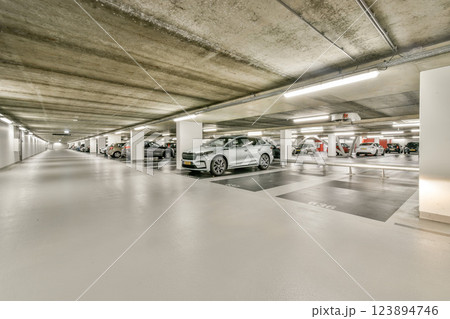 A spacious and well-lit underground parking garage featuring multiple parked cars and clean, minimalistic design, showcasing an efficient use of space and lighting. 123894746