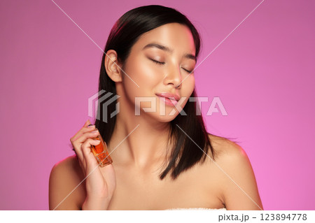 Model demonstrating skincare product application in a bright pink studio setting Model demonstrating skincare product application in a bright pink studio setting 123894778