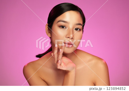 Beautiful model poses gracefully with soft lighting on pink background 123894852