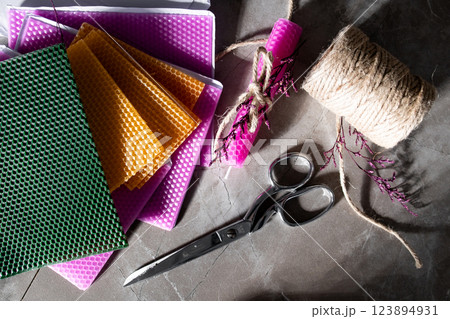 Colorful wax sheets with scissors twine and wrapped candle on a stone surface 123894931