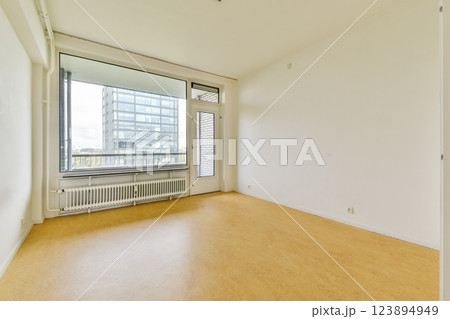 An empty room featuring large windows that let in ample natural light, showcasing a minimalist aesthetic ideal for various interior design concepts. 123894949