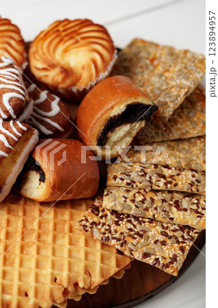 Assortment of sweet pastries and crispy snacks arranged on a wooden platter 123894957