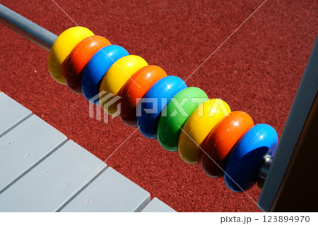 Colorful wooden counting beads shine in sunlight on a playground equipment during daytime outdoor playtime 123894970