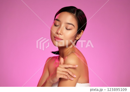 Portrait of a woman enjoying a moment of calm with closed eyes in a vibrant pink background 123895109