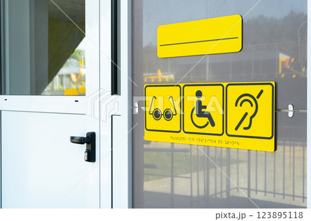 Accessibility signs displayed on the entrance of a public building for individuals with special needs 123895118