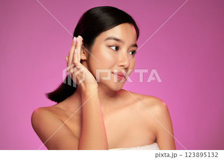 Woman applying skincare in front of a vibrant pink background during a beauty routine at home Woman applying skincare in front of a vibrant pink background during a beauty routine at home 123895132