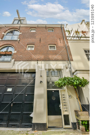 A striking view of a unique urban building facade featuring a mix of brick and modern design elements. Plants add a touch of greenery to the architecture. 123895140