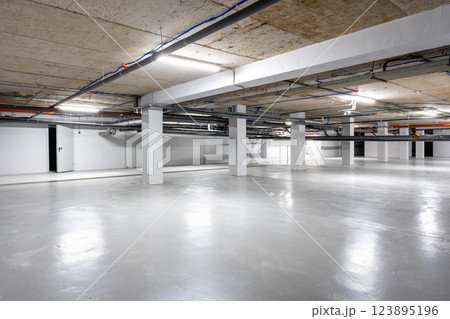 Spacious underground parking area featuring modern design and clean aesthetics in an urban location 123895196