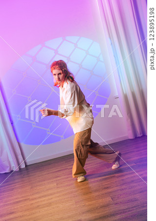 Contemporary dancer performs in stylish studio with colorful lighting and geometric projection at evening event Contemporary dancer performs in stylish studio with colorful lighting and geometric projection at evening event 123895198