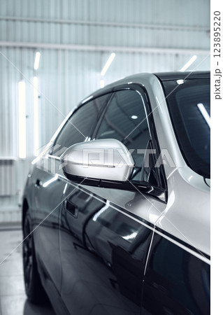 Sleek modern car with polished exterior showcases intricate side mirror design in well-lit workshop environment Sleek modern car with polished exterior showcases intricate side mirror design in well-lit workshop environment 123895220