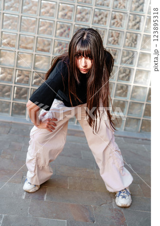 Dancer in urban environment showcases dynamic pose against glass wall 123895318
