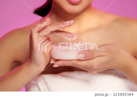 Woman applying cream during a skincare routine in a bright indoor setting 123895364