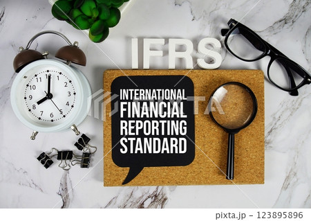 IFRS - International Financial Reporting Standard acronym with alarm clock and magnifying glass, business concept background 123895896