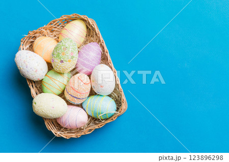 Colorful Easter eggs in wicker basket against colored background, closeup. top view with copy space Colorful Easter eggs in wicker basket against colored background, closeup. top view with copy space 123896298