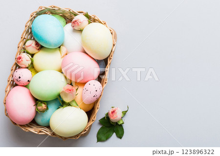 Happy Easter. Easter eggs in basket on colored table with yellow roses. Natural dyed colorful eggs background top view with copy space 123896322