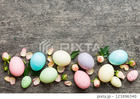 Happy Easter. Easter eggs on colored table with yellow roses. Natural dyed colorful eggs background top view with copy space 123896340