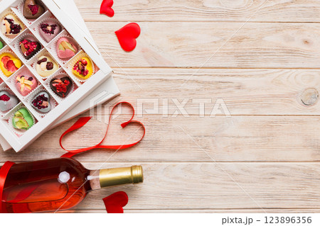 Bottle of red wine on colored background for Valentine Day with gift and chocolate. Heart shaped with gift box of chocolates top view with copy space Bottle of red wine on colored background for Valentine Day with gift and chocolate. Heart shaped with gift box of chocolates top view with copy space 123896356