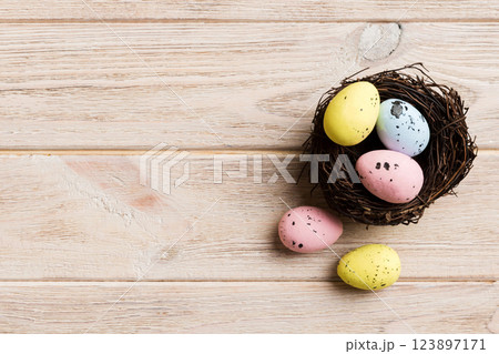 Colorful easter eggs in nest on table background with copy space top view Colorful easter eggs in nest on table background with copy space top view 123897171