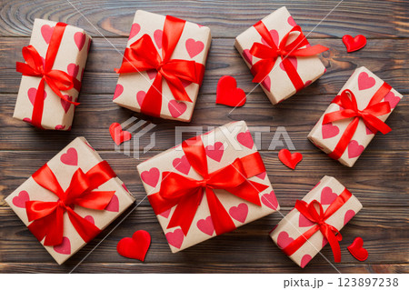 Top view photo of valentine day decorations gift box with red ribbon bow on colored background. Holiday gift boxes with top view Top view photo of valentine day decorations gift box with red ribbon bow on colored background. Holiday gift boxes with top view 123897238