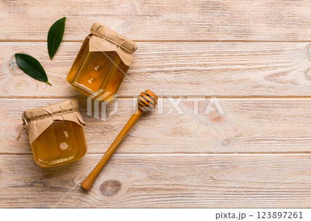 Honey jar with wooden honey dipper on white background top view with copy space. Delicious honey bottle Honey jar with wooden honey dipper on white background top view with copy space. Delicious honey bottle 123897261
