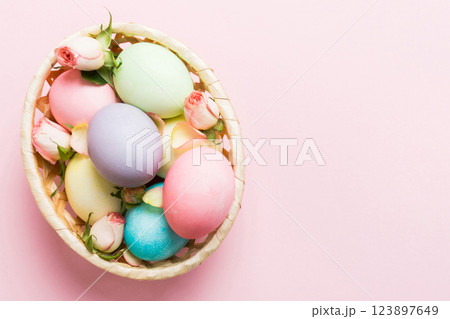 Happy Easter. Easter eggs in basket on colored table with yellow roses. Natural dyed colorful eggs background top view with copy space 123897649