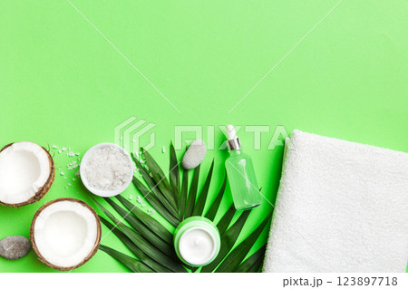 Coconut with jars of coconut oil and cosmetic cream on colored background. Top view. Free space for your text. Natural spa coconut cosmetics and organic treatment concept Coconut Spa composition 123897718