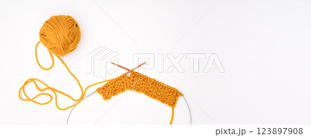 A ball of yarn with knitting needles on a light background A ball of yarn with knitting needles on a light background 123897908