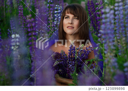 Happy romantic woman brunette with bouquet of flowers in lupine field Happy romantic woman brunette with bouquet of flowers in lupine field 123899898