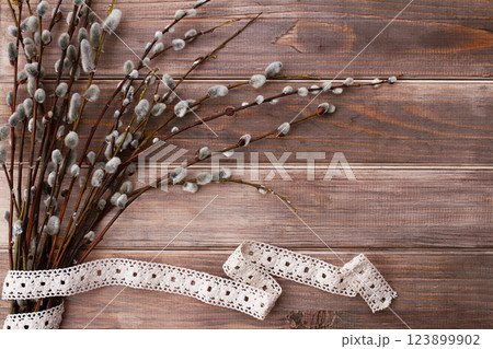 willow branches and cotton ribbon on brown old wooden background 123899902