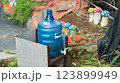 Outdoor water dispenser with plastic bottle in a garden setting view 123899949