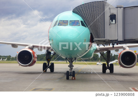 Boarding passengers on the plane through the boarding bridge. The plane lands at the international airport. Loading luggage. White airplane. Terminal Runway Boarding passengers on the plane through the boarding bridge. The plane lands at the international airport. Loading luggage. White airplane. Terminal Runway 123900808