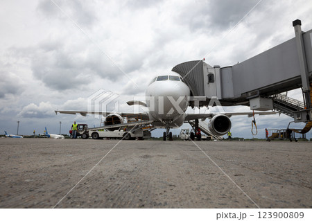 Boarding passengers on the plane through the boarding bridge. The plane lands at the international airport. Loading luggage. White airplane. Terminal Runway 123900809