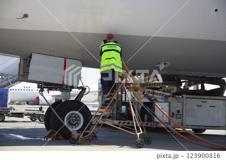 Refueling the plane at the airport. Male worker on the stairs. Refueling the plane at the airport. Male worker on the stairs. 123900816