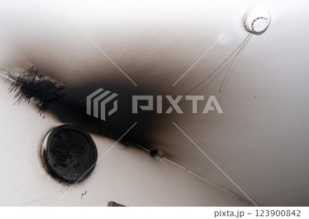 Burnt out LED lamp. A lampshade lamp on the wall after a fire. Spontaneous combustion and fire in a residential building. Burnt out LED lamp. A lampshade lamp on the wall after a fire. Spontaneous combustion and fire in a residential building. 123900842