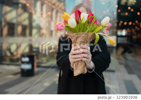 Amazed young woman extremely happy, hiding her face behind a bouquet of tulips in her hands, standing. Happy International Women's Day concept. Amazed young woman extremely happy, hiding her face behind a bouquet of tulips in her hands, standing. Happy International Women's Day concept. 123901936