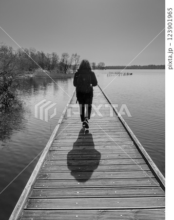 Explore serene wooden walkway over calm waters at Lac Biscarosse during bright daylight, surrounded 123901965