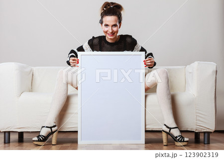 woman on sofa holding blank presentation board. 123902319
