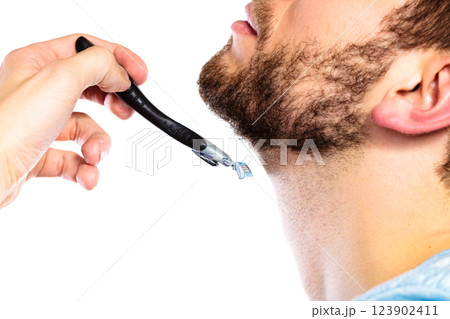 Young man with beard holding razor blade Young man with beard holding razor blade 123902411