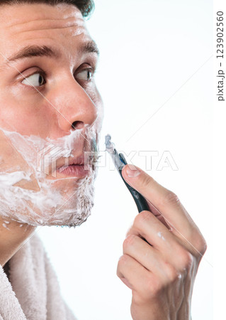 Young man shaving using razor with cream foam. Young man shaving using razor with cream foam. 123902560